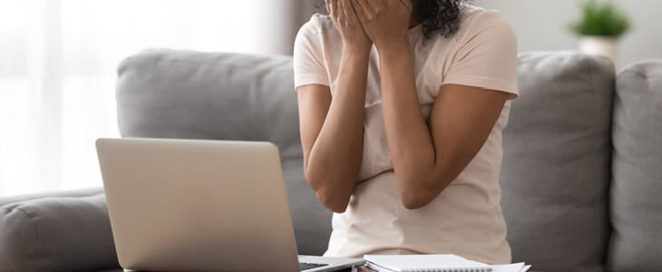 black woman crying while staring at a computer screen